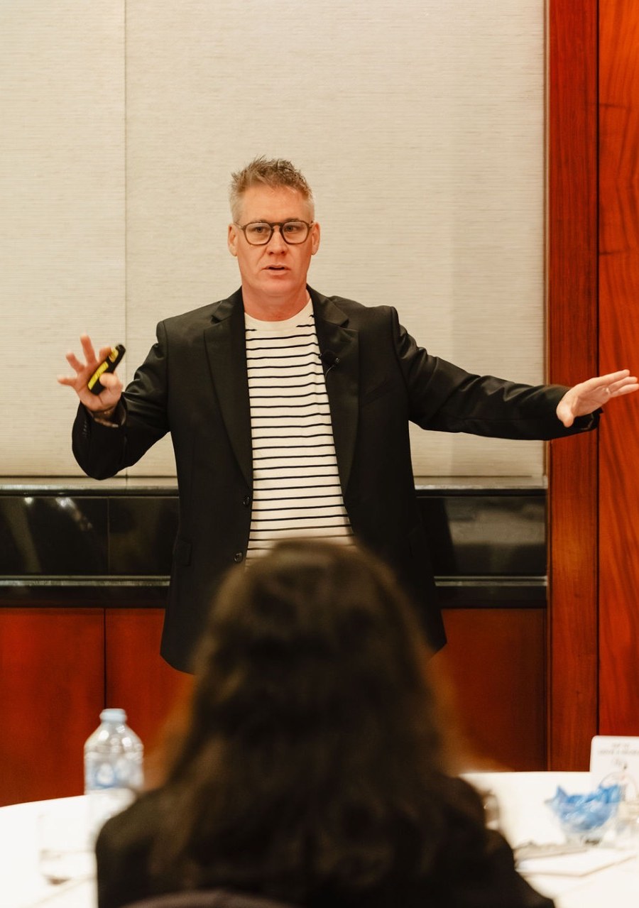 Mark Cameron addressing an executive audience seated around round tables